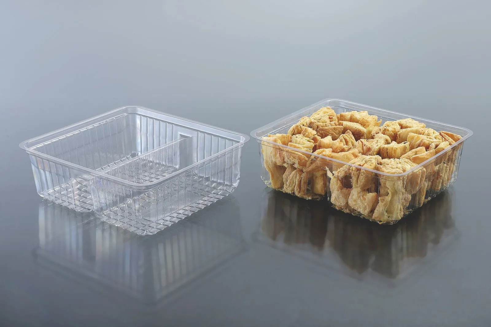Two Oracle PET bakery trays, one empty and one filled with a savoury snack mix